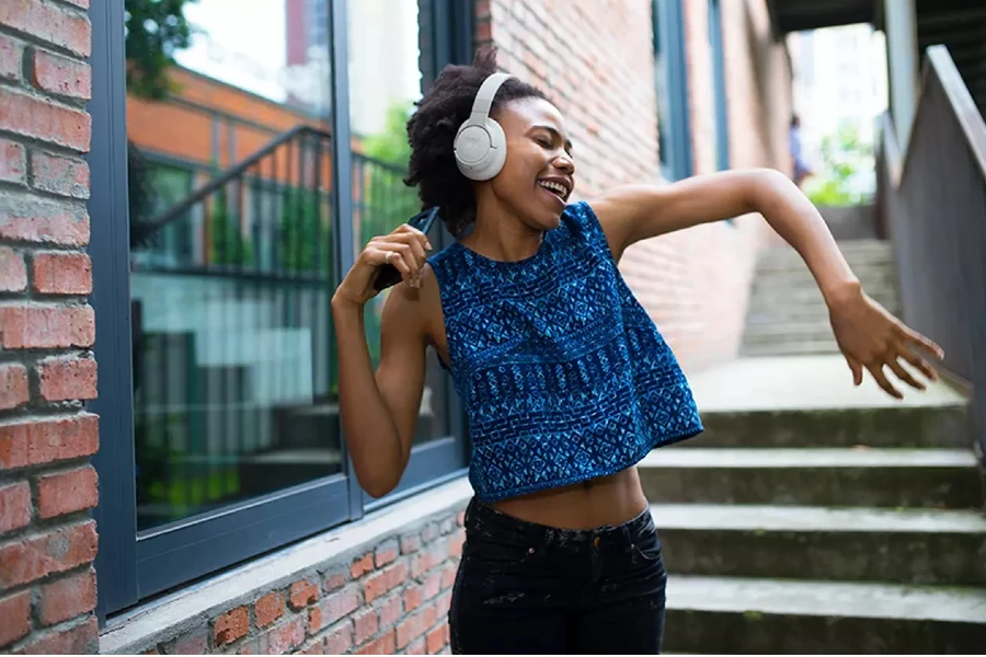 Mulher dançando com os fones de ouvido JBL Tune 770NC.